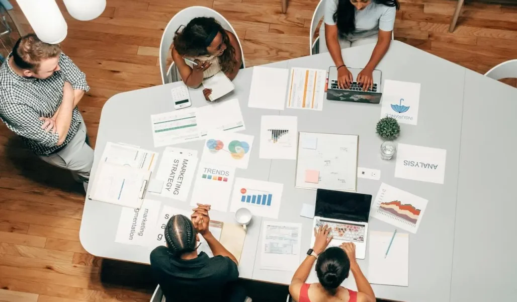 Profissionais discutindo estratégia de influencer marketing com gráficos e relatórios sobre a mesa.